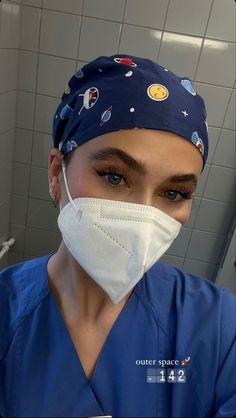 a woman in scrubs with a surgical mask on her face, looking at the camera