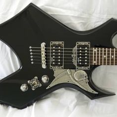 a black electric guitar laying on top of a white sheet