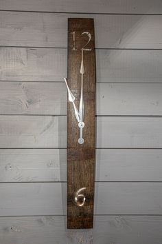 a wooden clock that is on the side of a white wall and has two hands