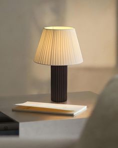 a lamp sitting on top of a table next to a book and remote control in front of it