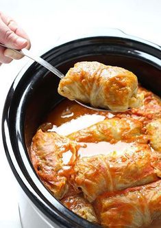 a crock pot filled with meat covered in gravy and garnished with a spoon