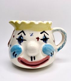 a close up of a ceramic jug with a clown face on it's side