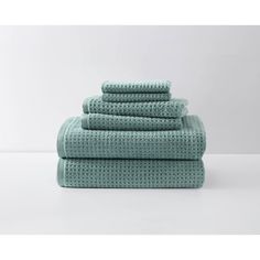 four towels stacked on top of each other in teal green color with white background