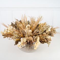 an arrangement of dried flowers in a glass vase