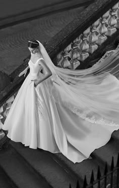 a woman in a wedding dress and veil walking down the stairs with her hand on her hip