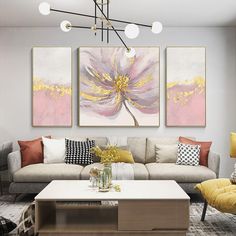 a living room filled with furniture and two paintings on the wall above each couches