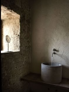 a white sink sitting next to a window in a room with stone walls and flooring