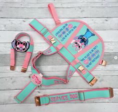 a pink and blue dog harness with two matching leashes on a wooden floor next to it