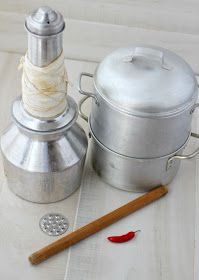 two metal containers and a wooden stick on a white tablecloth with red chili peppers next to them