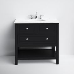 a white sink sitting next to a black cabinet with two faucets on it