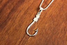 a fishing hook necklace on a wooden table