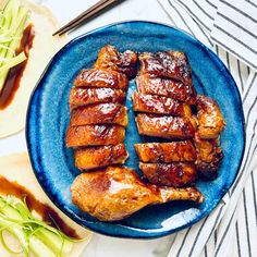 some meat is on a blue plate with chopsticks and sauce next to it