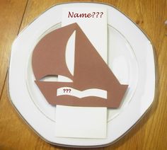 a white plate topped with a paper cut out of a sailboat