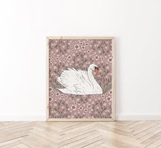 a white swan sitting on top of a wooden floor in front of a flowery wall