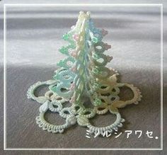 there is a small crochet christmas tree on the table next to two rings