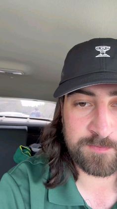 a man with long hair wearing a hat and looking at the camera while sitting in a car