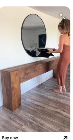 a woman is standing in front of a mirror and looking at her reflection on the wall