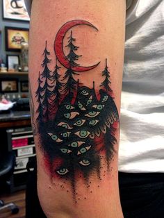 a man with a tattoo on his arm that has trees and an moon in the background