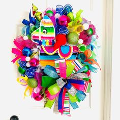 a colorful wreath is hanging on the front door, decorated with bright ribbons and decorations