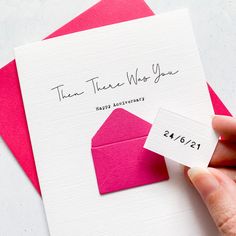 a person holding a pink envelope with a stamp on it