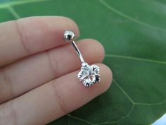 a person is holding a tiny silver nose ring with a flower design on the end