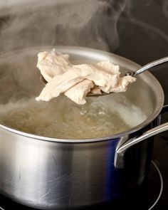 chicken being cooked in a saucepan on the stove with steam coming from behind it