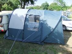 a tent is set up in the grass next to two parked campers and a car