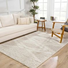 a living room with white furniture and wood flooring, including a couch and chair