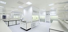 an empty laboratory with white counters and sinks in the center is filled with lots of light