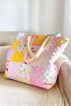 a pink and yellow patchwork bag sitting on top of a couch