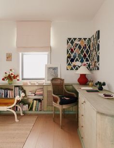 a living room filled with furniture and bookshelves next to a window on top of a hard wood floor