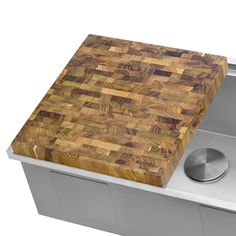 a large wooden cutting board sitting on top of a metal sink next to a faucet