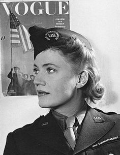 a black and white photo of a woman in uniform with an american flag on the wall behind her