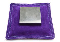 a purple velvet case with a silver square on it and stitching around the edges