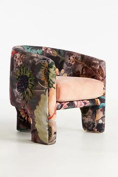 an upholstered chair with floral fabric on the back and pink seat cushion, in front of a white background