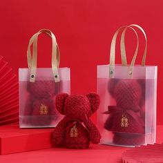 two bags with teddy bears in them sitting next to each other on a red surface