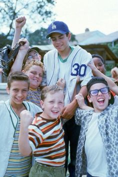 a group of young boys standing next to each other with their arms in the air