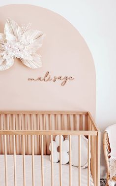 a baby's room with a crib, teddy bear and name on the wall