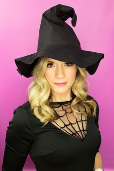 a woman with blonde hair wearing a black witches hat on top of her head and looking at the camera