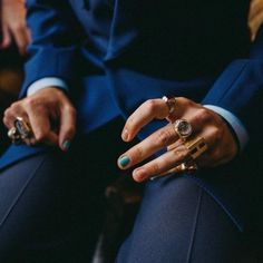 a person in a blue suit with rings on their fingers and two other people's hands