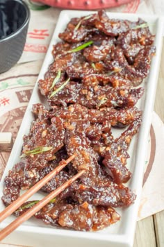 some food is on a white plate with chopsticks