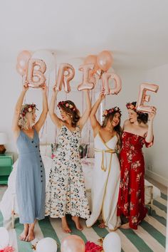 three women holding up balloons in the shape of letters that read'b'and e