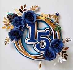 a blue and gold birthday cake with flowers on it's top that reads fifteen