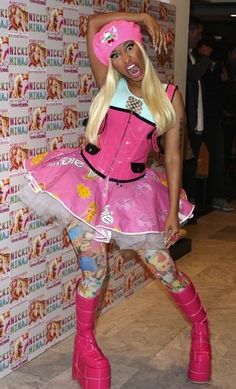 a woman dressed in pink is standing next to a wall and posing for the camera