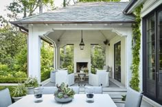 an outdoor dining area with white furniture and greenery