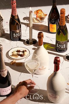 a table topped with lots of bottles of wine next to plates of food and drinks