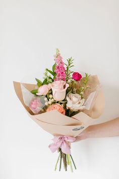 a person holding a bouquet of flowers in their hand with pink and white blooms on it