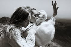 two women standing on top of a mountain kissing each other with their hands in the air