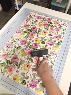 a person is using a roller to cut out flowers on a piece of paper with scissors