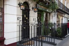 a woman is walking down the sidewalk in front of a building with wrought iron gates